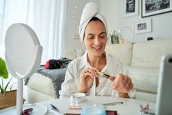 Smiling woman testing foundation on hand with brush