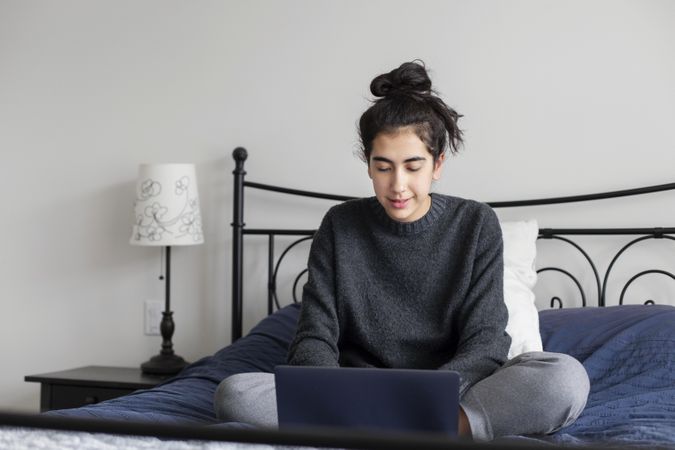 Young female on her bed using a laptop