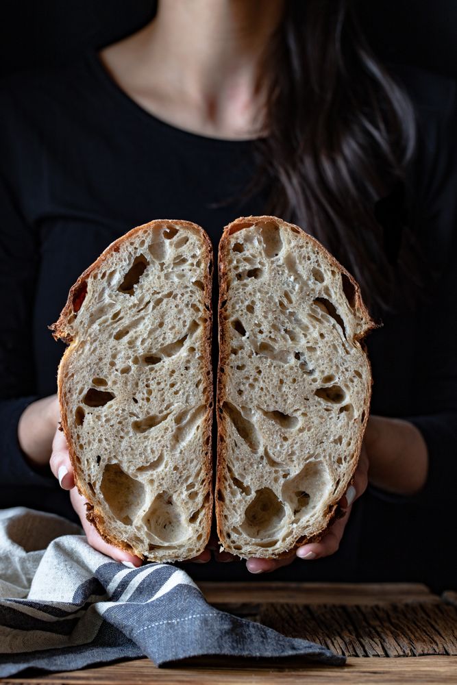 Crop person holding halved seeded bread