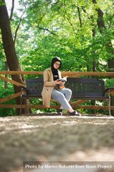 Woman in headscarf relaxing in park with book bxL6rb