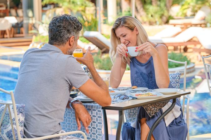 Cheerful couple enjoying beverage in tropical resort cafe