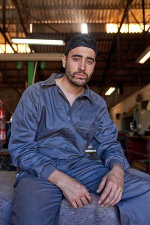 Confident male mechanic sitting on stone bench