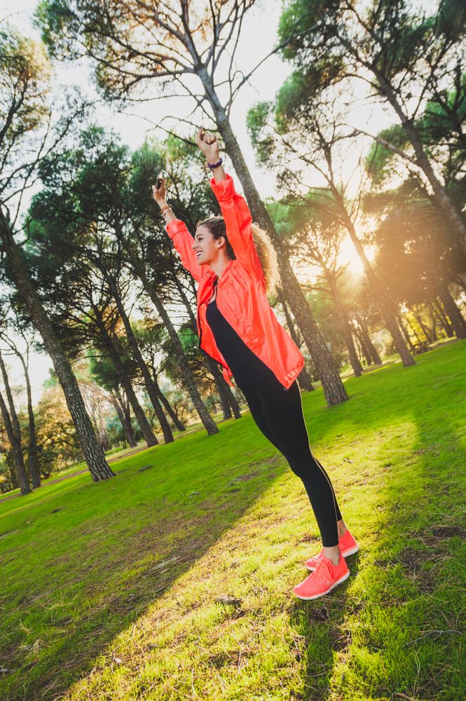 Excited sportswoman with arms raised in park