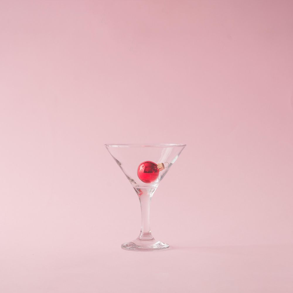 Christmas tree decoration in martini glass on pastel pink background with creative copy space