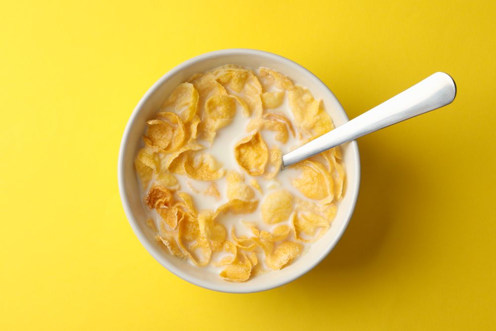 Bowl with muesli and milk on yellow background