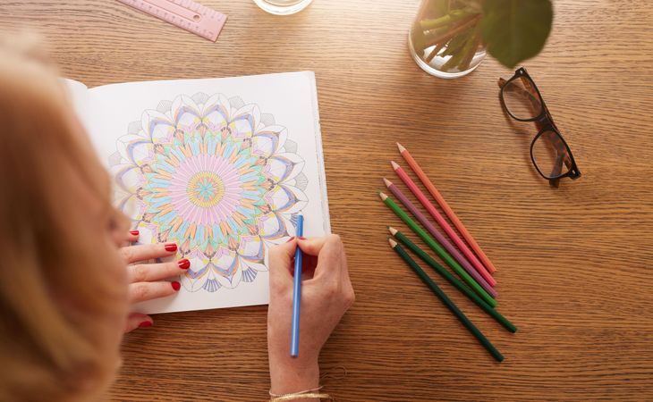 Close up view of female coloring a mandala in book