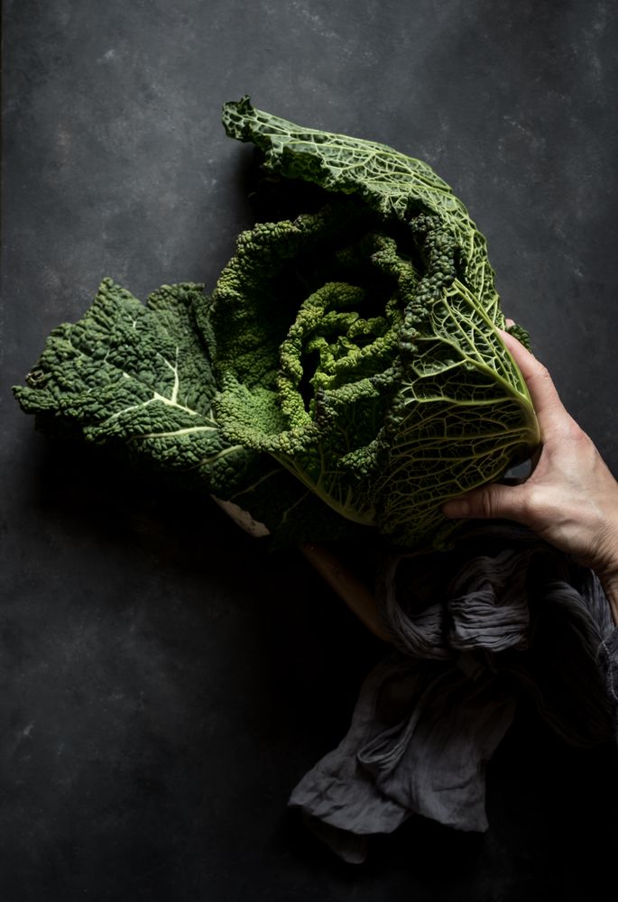 Woman holding fresh cabbage on table