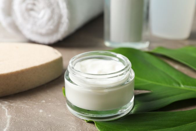 Palm leaves, cream, sponge, shower gel, shampoo and towel, close up