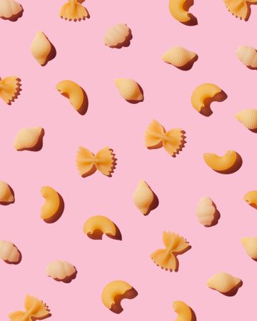Multiple types of pasta over pink background