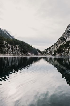 Wonderful lake between hills in snow and cloudy sky
