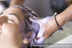 Female with head back and eyes closed having hair washed in salon bGLDl0