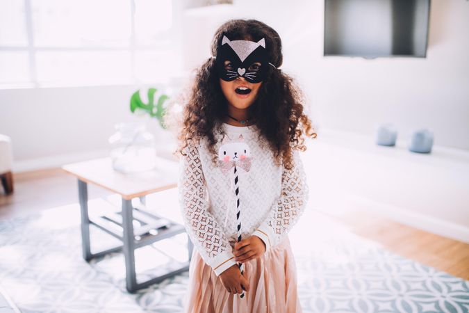 Little girl wearing a mask holding a wand