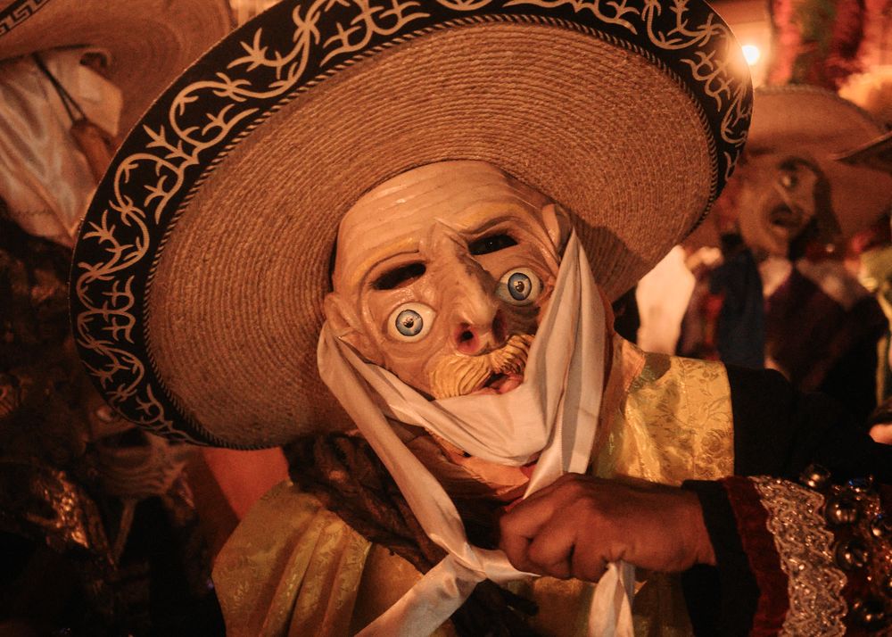 Person with mask and sombrero at Mexican festival