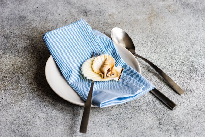 Sea shells on table setting with blue napkin