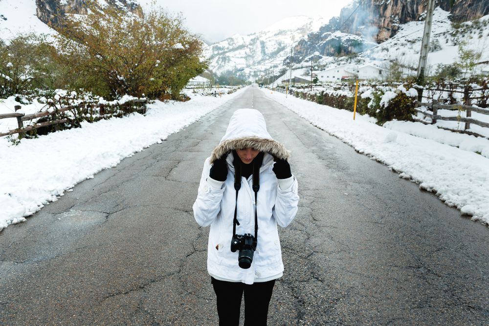Content woman taking picture in snowy mountains