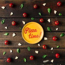 Basil, tomatoes, and cheese on wooden background with plate and “Pizza time!” text