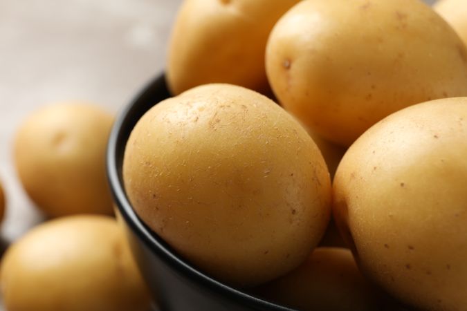 Close up of fresh potatoes in a dark ceramic bowl