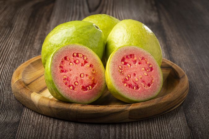 Fresh sliced guavas on wooden table.