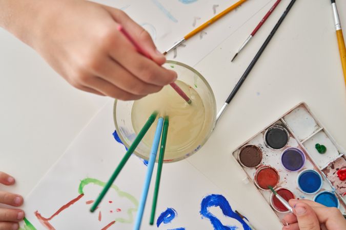 Crop artist washing aquarelle off paintbrushes
