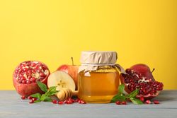 Apples, pomegranate, and honey pot in bright yellow room
