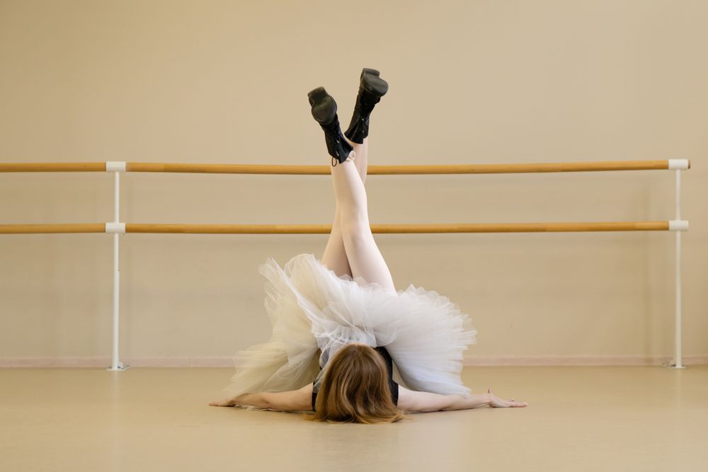 Ballerina in shoes and tutu, performing floor pose