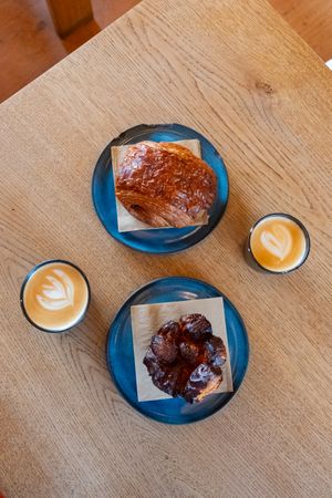 Top view of breakfast roles and cappuccinos on wooden table