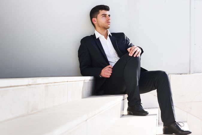 Man in suit resting on stairs outside