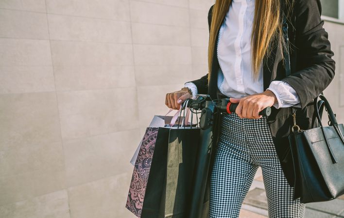 Unrecognizable woman with shopping bags on electric scooter