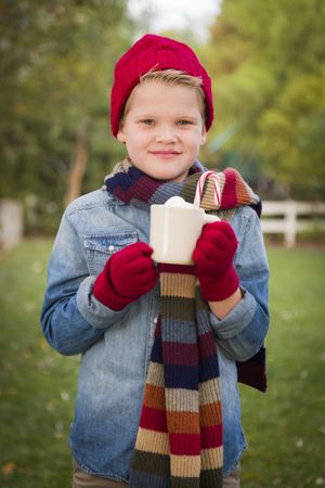 Young Boy in Warm Clothing Holding Hot Cocoa Mug Outside