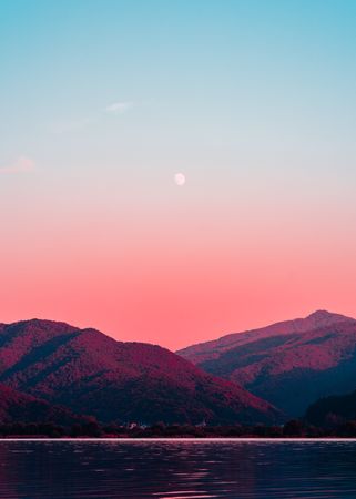 Two mountains under pink sky