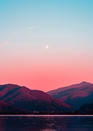 Two mountains under pink sky