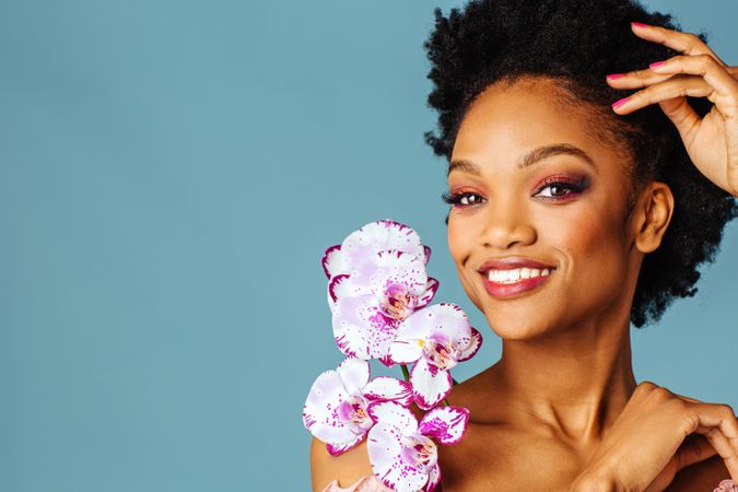 Studio beauty shot of a smiling Black woman with purple flowers