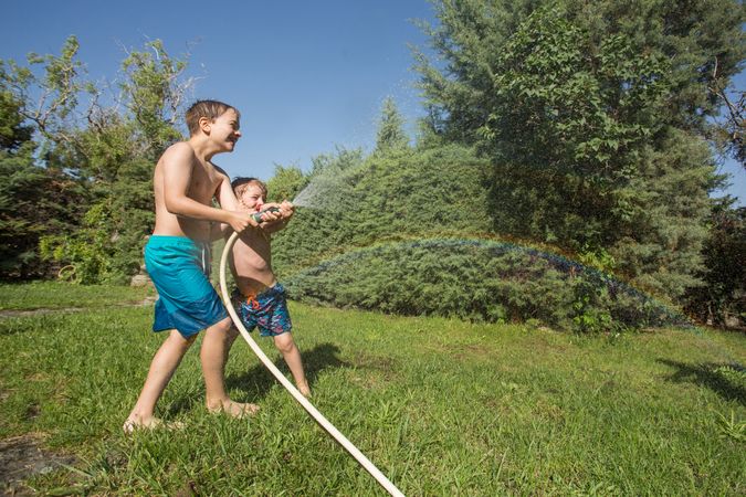 Little kids in swimwear having fun with splashing water