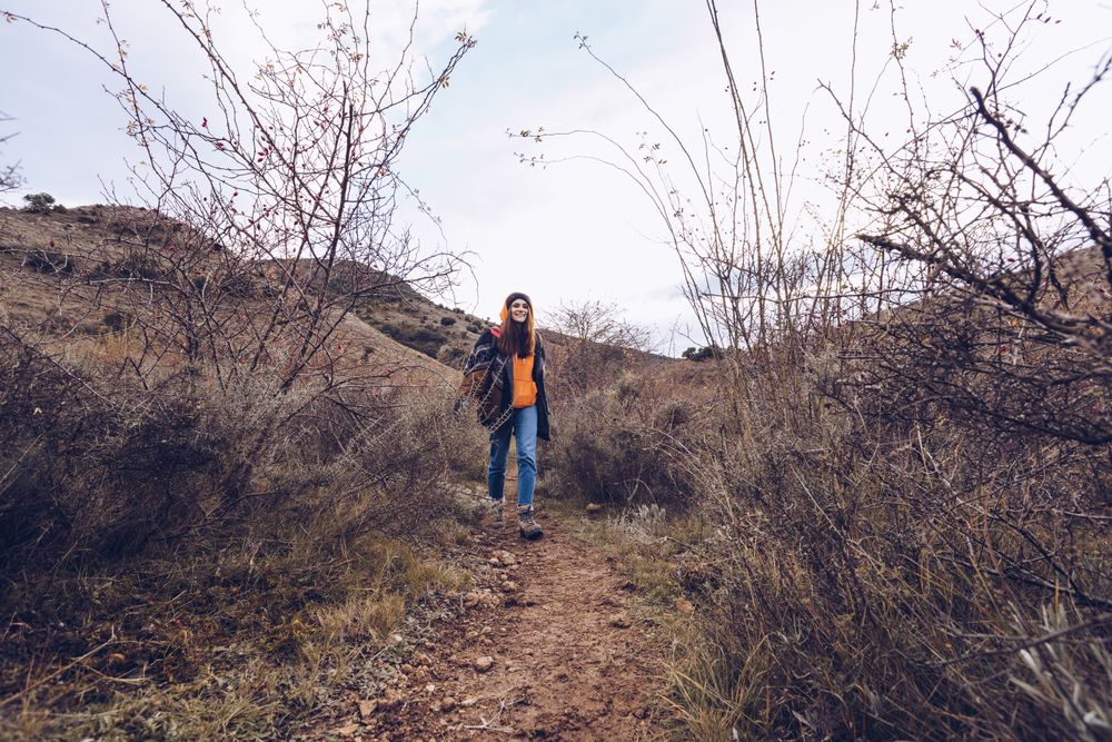 Hiker with backpack walking along pathway in autumn forest