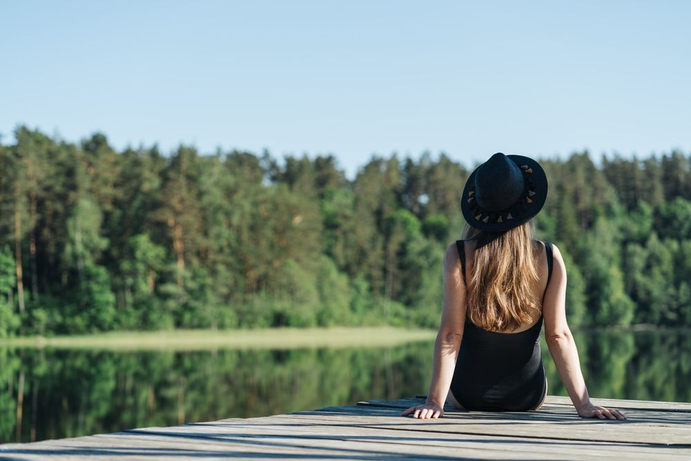 Young female sitting on pier on nature