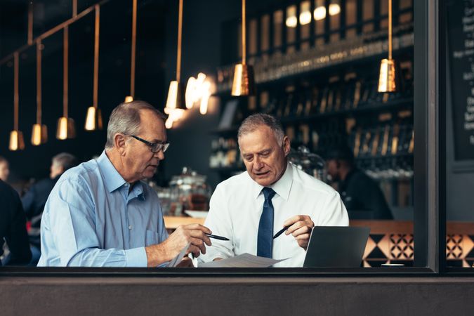 Two serious men discussing business contract in a cafe
