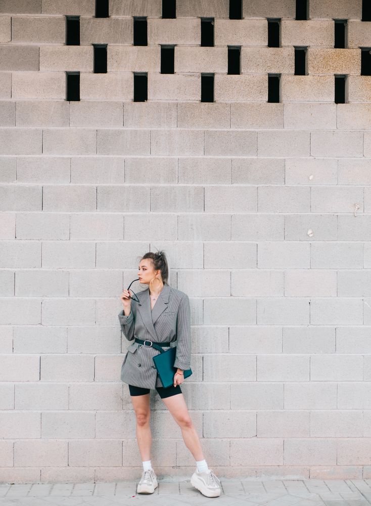 Stylish businesswoman with laptop leaning on wall