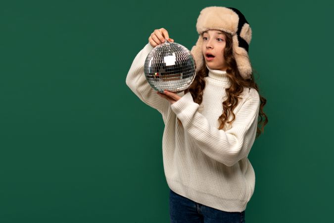 Surprised girl in winter hat looking at disco ball.