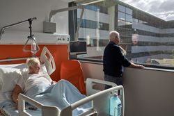 Thoughtful mature man standing near window during visit of unwe