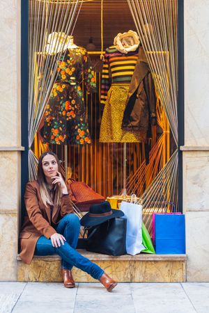 Content young woman in casual outfit resting on street after shopping