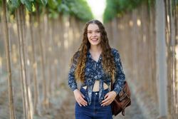 A Young Woman Smiling Happily in a Vineyard Surrounded by Beautiful Lush Green Rows
