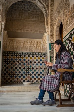 Asian woman in ancient palace using mobile phone