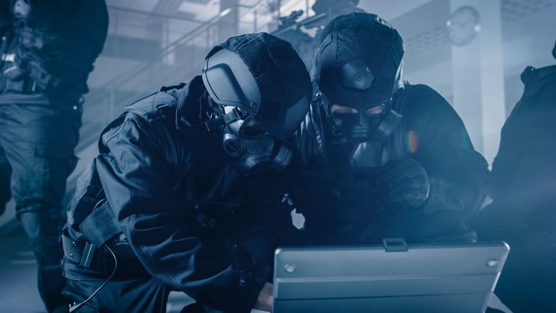Masked Team of Armed SWAT Police Officers with Rifles are in Dark Seized Office Building with Desks and Computers.
