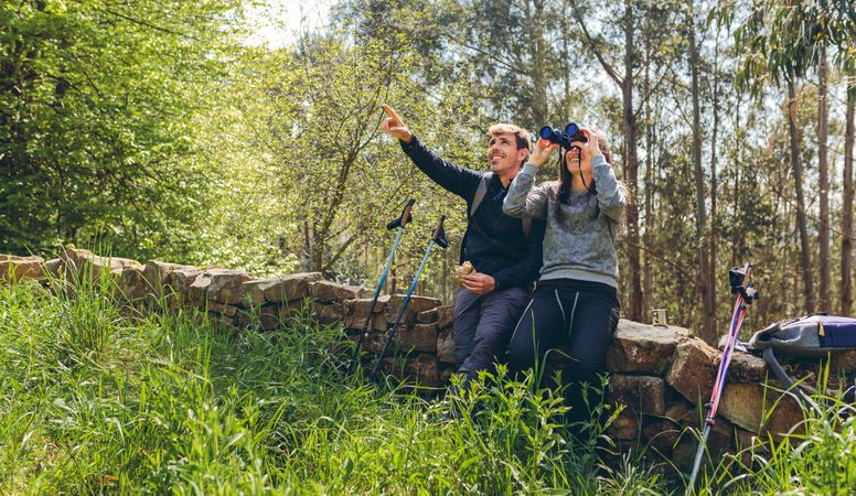 Couple doing trekking looking with binoculars
