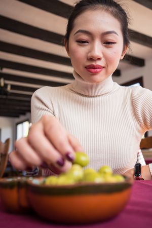 Asian woman eating olives in restaurant