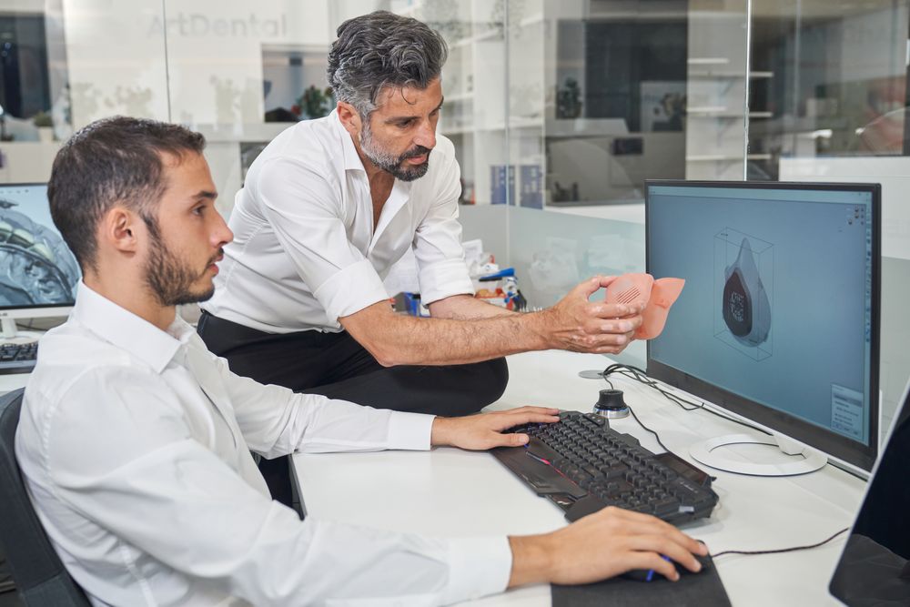 Workers checking 3D respirator near computer