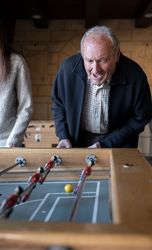 A granddaugther and his grandfather are playing table football game and having fun together