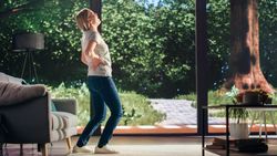 Young Adult Female Standing Up from a Couch at Home and Experiencing Back Pain in a Result of Spine Trauma.