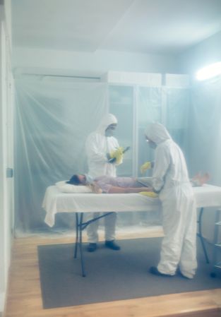 Doctors in bacteriological protection doing medical check to patient lying on a gurney