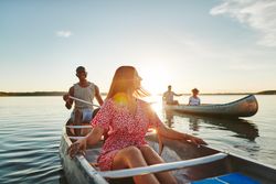 A woman taking a break from paddling on a canoe to enjoy the view